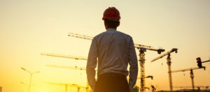 Construction worker at sunset looking at multiple cranes to promote Greenfield Risk Solutions Insurance Brokers - Construction Insurance